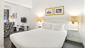 A hotel room with a large bed, two bedside lamps, a flat-screen TV, a desk, and a chair. - Inner-City Studio – Walk to Everything! (Melbourne)