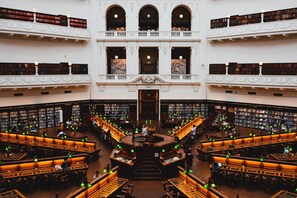 A multi-level library with bookshelves, reading areas, and a central staircase. - Inner-City Studio – Walk to Everything! (Melbourne)