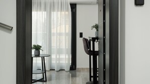 Ingresso moderno di un hotel con una porta in legno scuro, una targa con il numero '501', un tavolino con una pianta e una sedia.