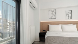 Una camera d'albergo moderna con una grande finestra, un letto con lenzuola bianche e due opere d'arte astratte alle pareti.