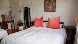 A bedroom with a large bed, two pillows, a nightstand, a lamp, a wall art piece, and a door leading to another room. - Towncottage Tenterfield Stay with Scenic Views (Tenterfield)