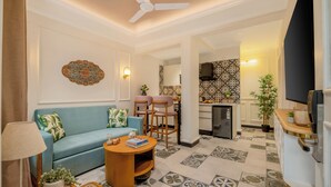 A living room with a sofa, chairs, a coffee table, a lamp, and a television. - Staymaster Veridian 2BR - Standard (Calangute)