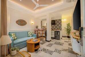 A living room with a sofa, chairs, a coffee table, a lamp, and a television. - Staymaster Veridian 2BR - Standard (Calangute)