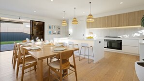 Eine moderne Küche mit Essbereich, Holzboden, Pendelleuchten und Blick ins Freie.
