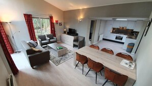 A modern living room with a sofa, coffee table, and dining area with chairs. - 6-person Comfort Bungalow With Sauna (Kootwijk)