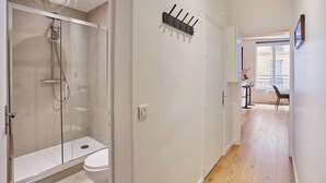 Ein modernes Badezimmer mit Duschkabine aus Glas, einer weißen Toilette und einem Flur, der in einen Essbereich mit Blick führt.