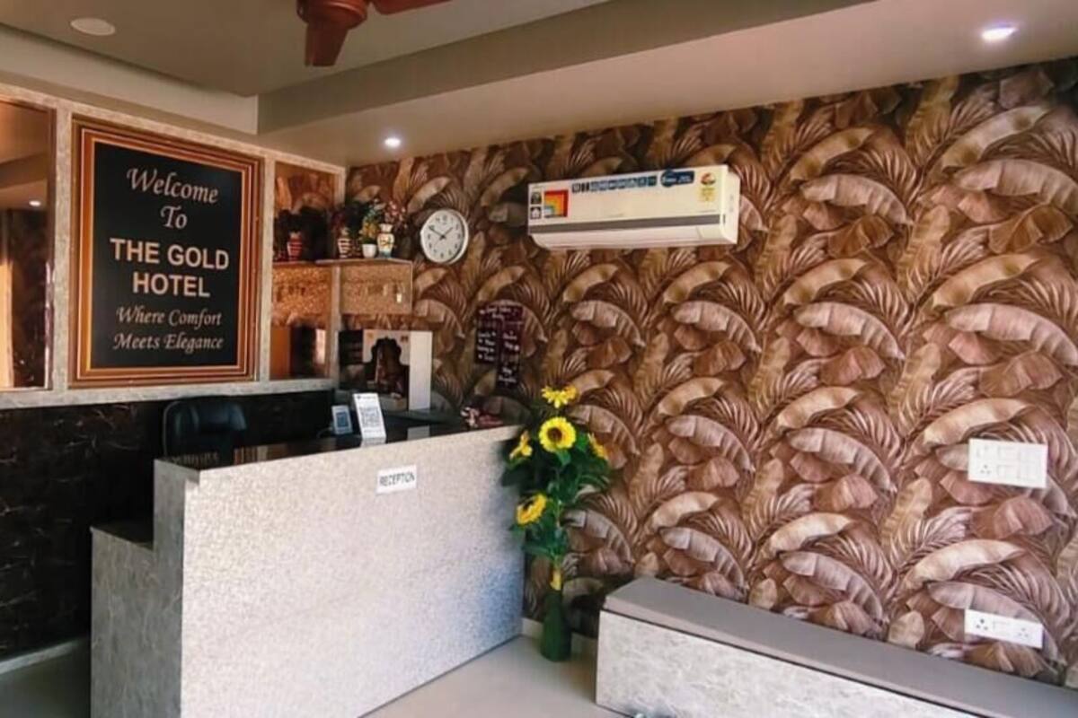 A reception area with a sign reading 'Welcome to The Gold Hotel,' a clock, and a floral arrangement.