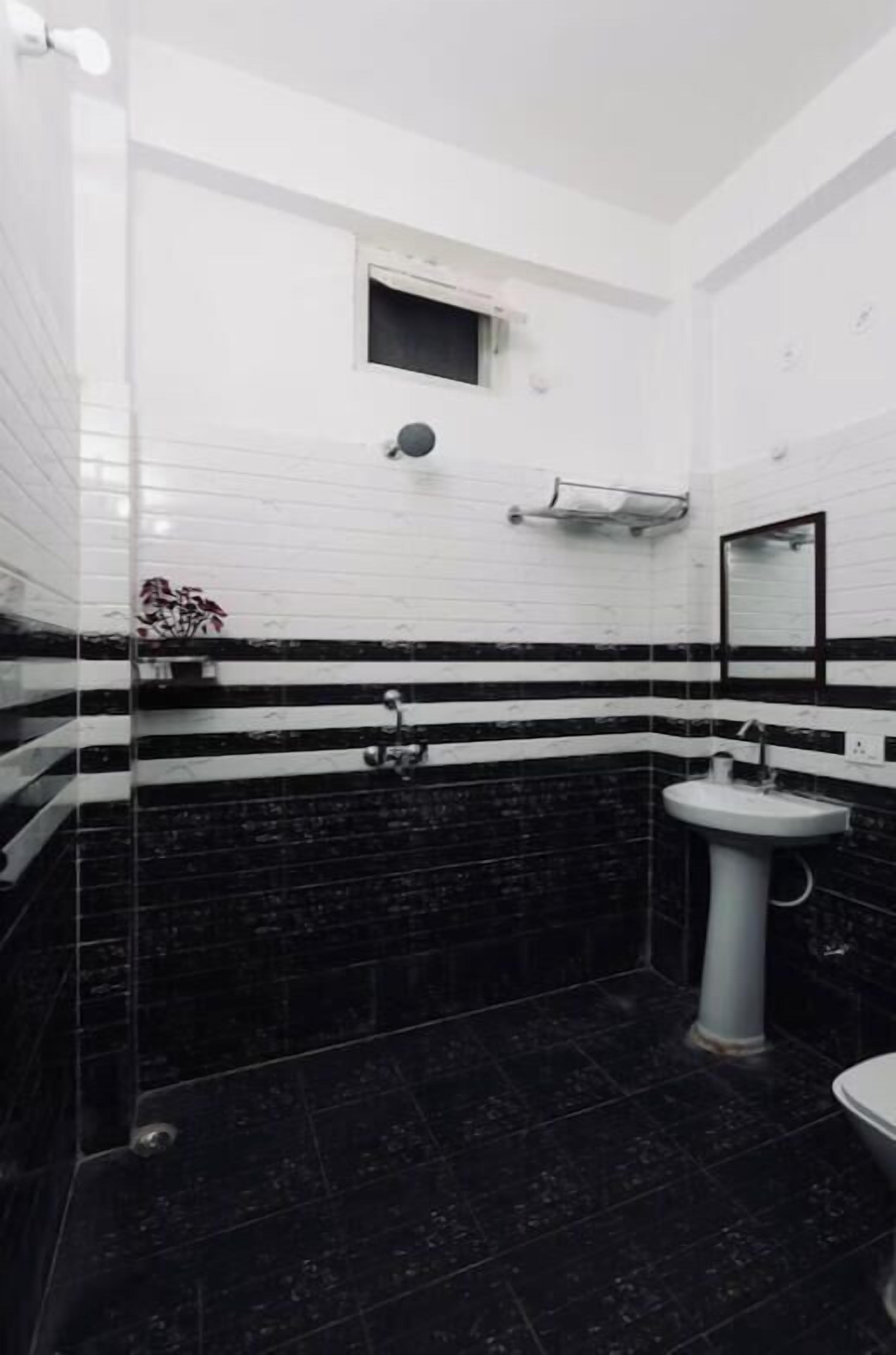 A bathroom with black and white striped tiles, a white sink, and a small window.