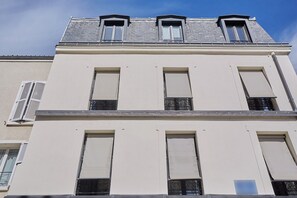 Ein mehrstöckiges Gebäude mit großen Fenstern, einer flachen Dachfläche und einer weißen Fassade.