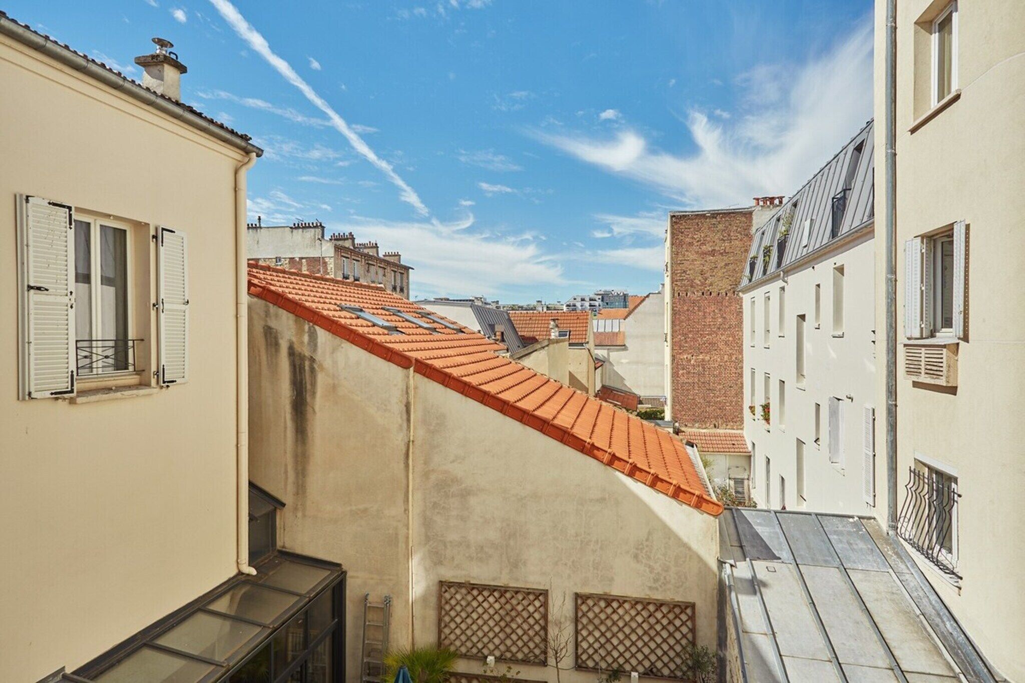 A narrow street with buildings on both sides, featuring red-tiled roofs and white walls.