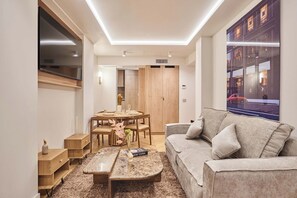 A modern living room with a sofa, a dining table, and a large window with a city view. - Elegant appartement with AC - Paris Montorgueil (Paris)