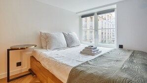 Ein Schlafzimmer mit einem Bett, einem Fenster und einem kleinen Tisch.