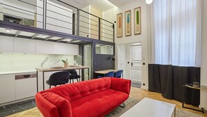 Eine moderne Wohnung mit einem roten Sofa, einem Essbereich, einer Küche und einer Wendeltreppe zu einer oberen Ebene.