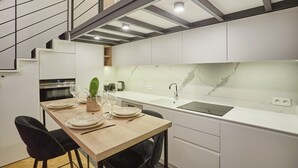 Eine moderne Küche mit Marmorfliesenspiegel, einem Esstisch für vier Personen und einer Treppe, die in ein Obergeschoss führt.