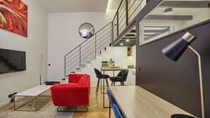 Ein modernes Wohnzimmer mit einem roten Sofa, einem Holzesstisch und einer Treppe, die in eine obere Ebene führt.