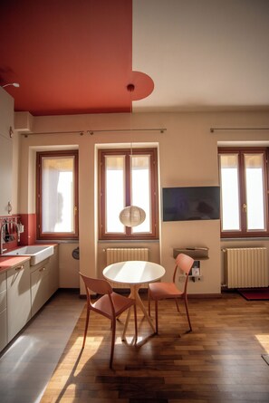 A modern kitchen with a dining area, wooden flooring, and a large window. - The Haven Suite in Duomo (Milano)