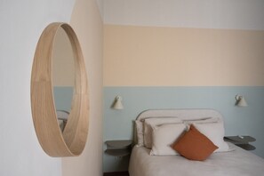 A bedroom with a bed, a wooden-framed mirror, and bedside lamps. - The Haven Suite in Duomo (Milano)