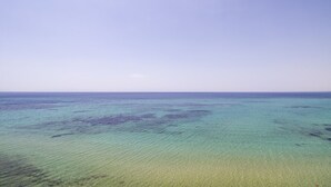 Une vue dégagée sur une plage aux eaux peu profondes, avec un horizon lointain.