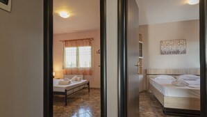 Une chambre d’hôtel comprenant un lit, une table de chevet, une fenêtre avec des rideaux et une œuvre d’art accrochée au mur.