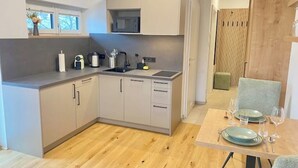 Una cocina moderna con armarios grises, un microondas integrado y un comedor con una mesa para dos.