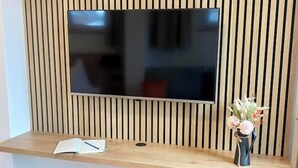Televisor de pantalla plana montado en una pared de madera, con un escritorio de madera debajo.