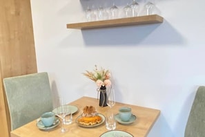 A dining table with a vase of flowers, a plate of food, and a wine glass. - Apartments Classic (Tauplitz)