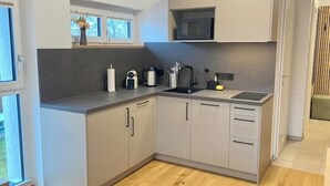 Una cocina moderna con gabinetes grises, encimera negra, microondas integrado y una ventana con vistas.