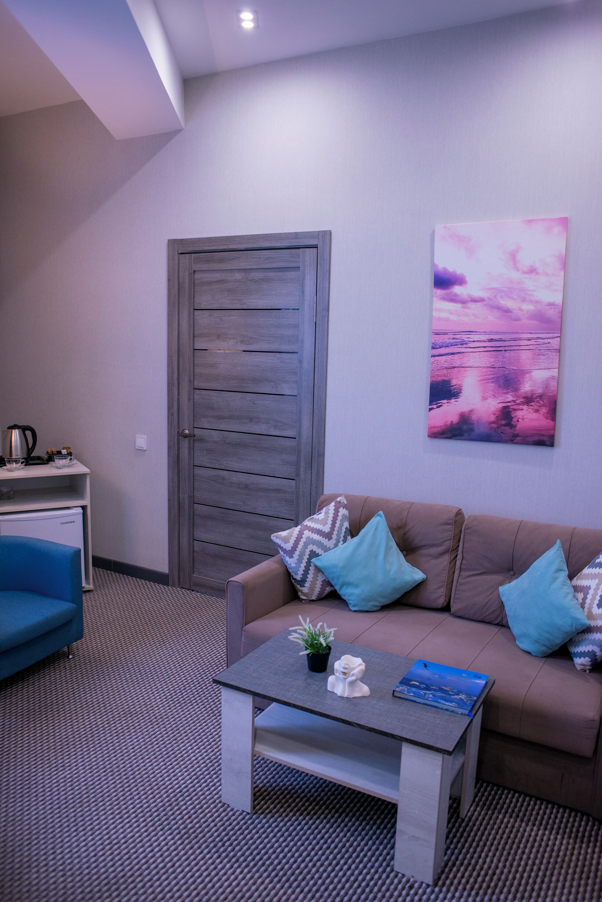A modern living room with a sofa, coffee table, and a painting on the wall.