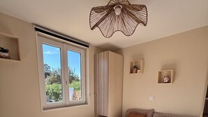 Ein Schlafzimmer mit einem großen Bett, einem Fenster, einem Deckenventilator und Blick auf Grünfläche.
