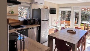 Eine moderne Küche mit Essbereich, großen Fenstern und Blick ins Freie.