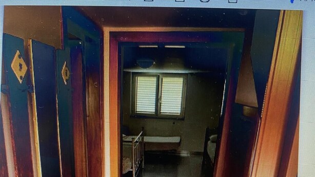 Een gang die leidt naar een kamer met een raam, een deur en een bank.
