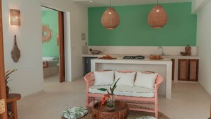 Una sala de estar con un sofá, una mesa de centro y una cocina con mostrador y armarios.