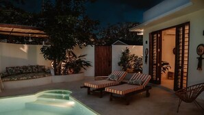 Zona de piscina con sillas de descanso, un sofá y un espacio de estar techado.