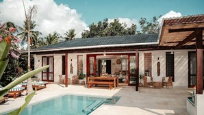 Une maison avec une piscine, du mobilier d’extérieur et un patio couvert.