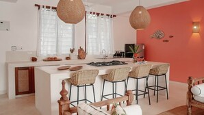 Une cuisine moderne dotée d’un îlot central, de tabourets de bar et de luminaires suspendus.
