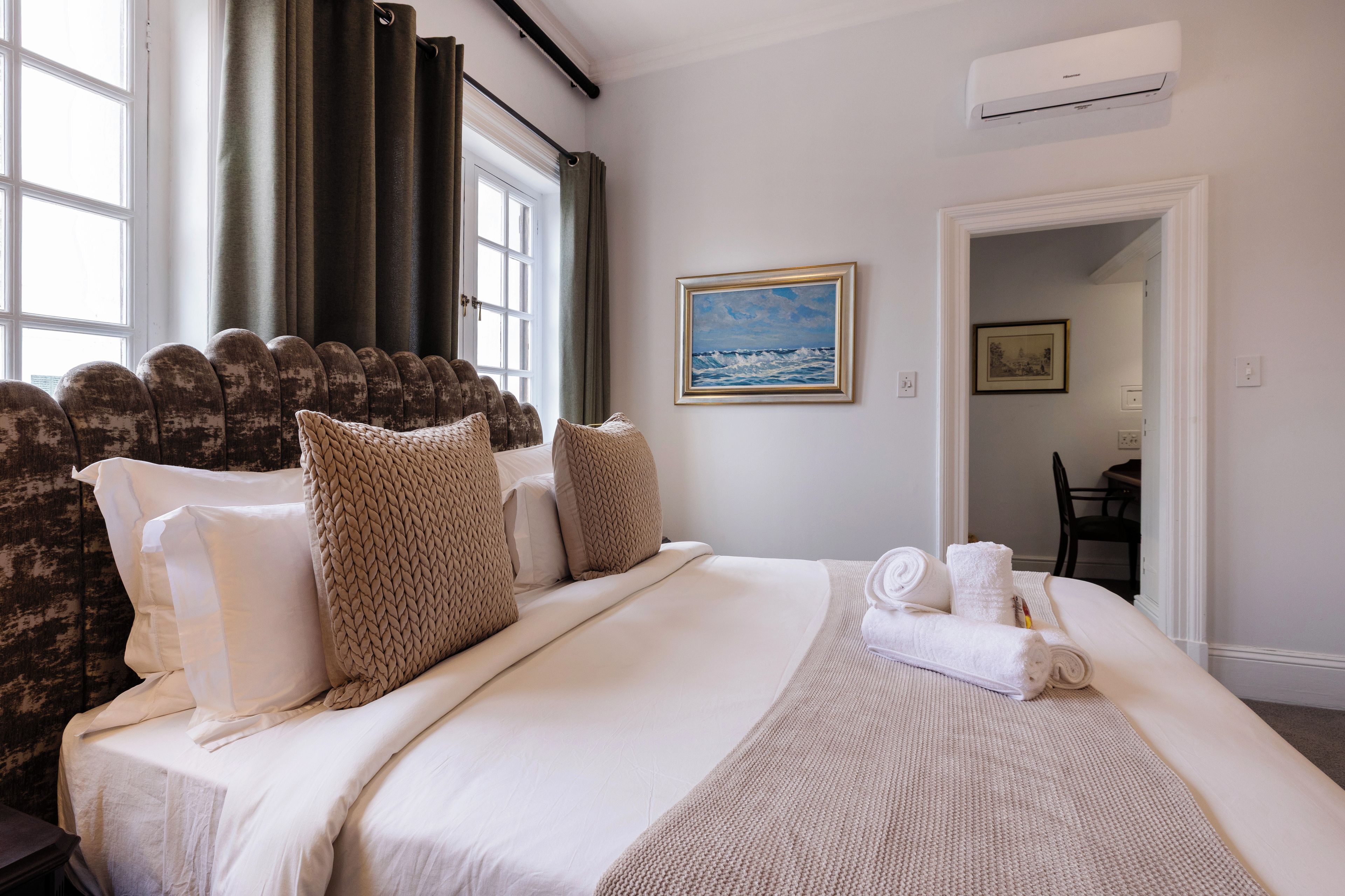 Habitación de hotel con una cama grande, un cuadro en la pared y un equipo de aire acondicionado.