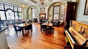 A spacious room with a piano, dining tables, and chairs. - The Cape Town Club (Cape Town)