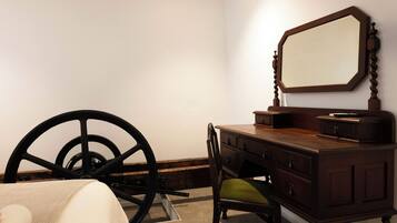 Una habitación con un aparador de madera, una silla, un espejo grande y una rueda grande.