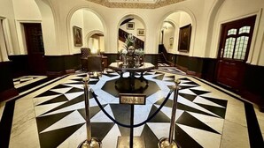 A grand lobby with a geometric patterned floor, a central table with a 'PRIVATE' sign, and a chandelier. - The Cape Town Club (Cape Town)