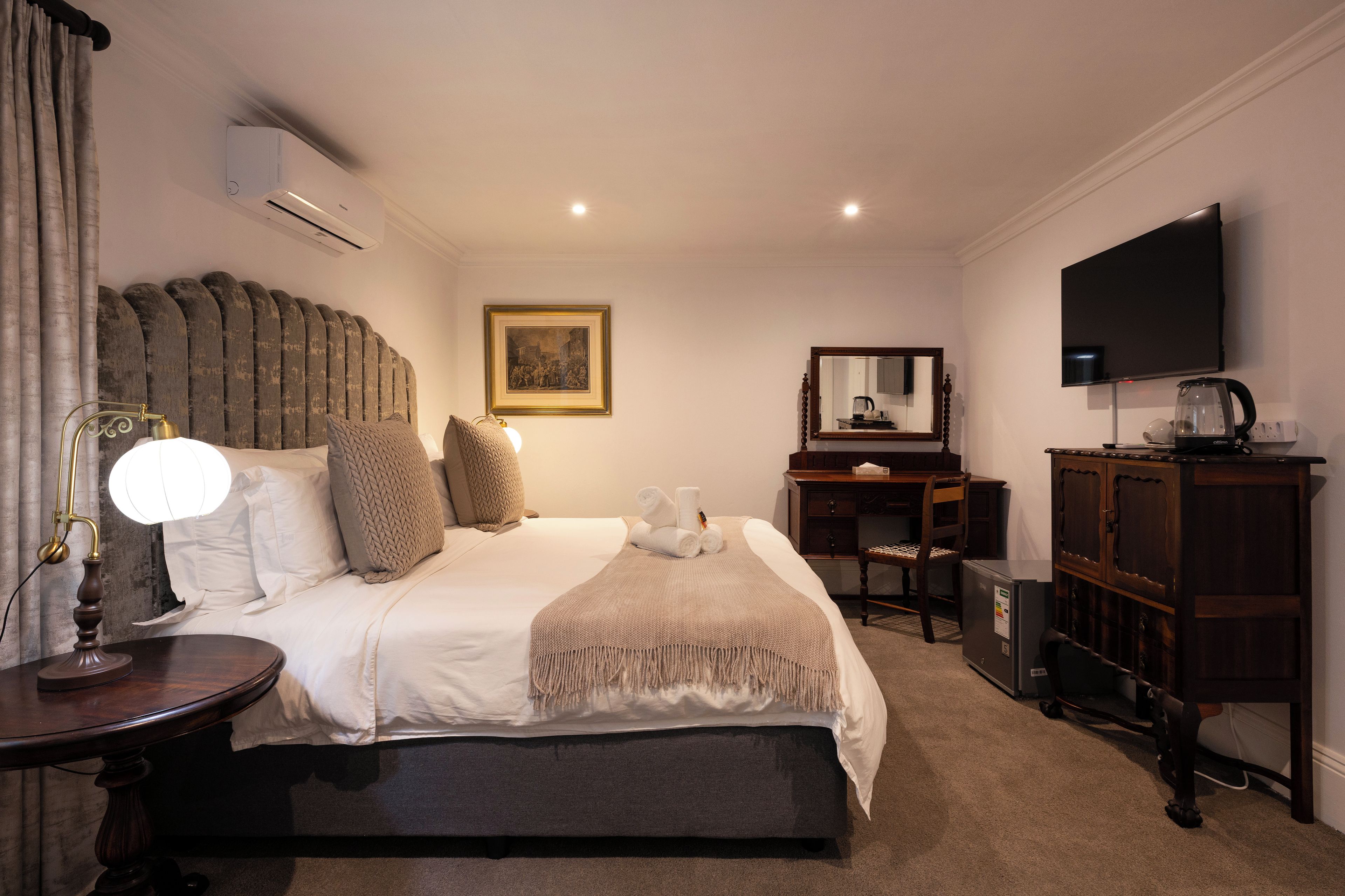 A hotel room with a large bed, a desk, a television, and a wardrobe.