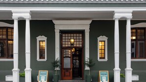 A building facade with a central entrance, flanked by two columns, and two potted plants. - The Cape Town Club (Cape Town)