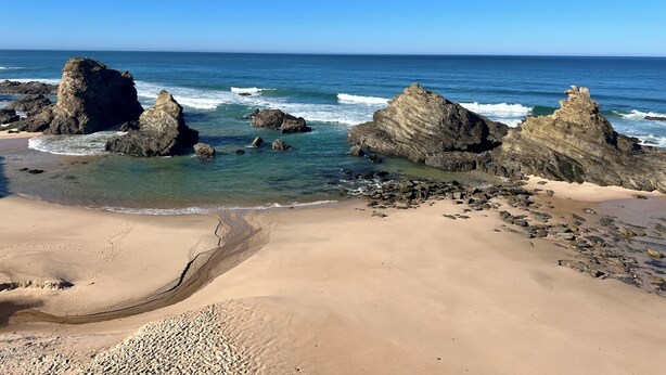 Una playa con grandes formaciones rocosas y agua azul cristalina.