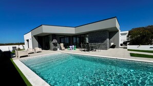 Una casa moderna con piscina, mobiliario exterior y vistas al paisaje.