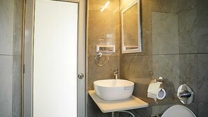 Un baño con un lavamanos blanco, un inodoro, un espejo y una puerta.