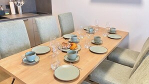 A dining table set with plates, bowls, and glasses, surrounded by upholstered chairs.