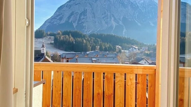A mountain view from a balcony with a wooden railing.