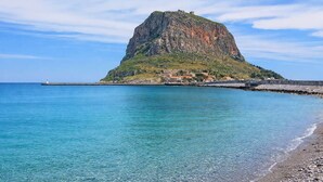 A coastal town with a prominent rocky hill, clear blue waters, and a lighthouse. - Matroni's House - Seafront Getaway in Monemvasia (Gefira)