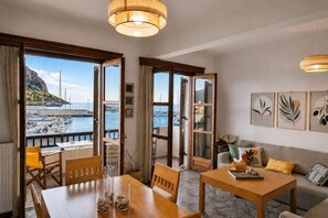 Ein Zimmer mit Holztisch, Stühlen, einer Couch und Blick auf einen Yachthafen mit Booten.