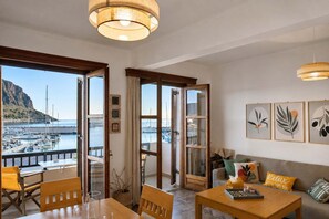Ein Zimmer mit Blick auf eine Marina, einem Holztisch, einer Couch und gerahmten Kunstwerken an der Wand.