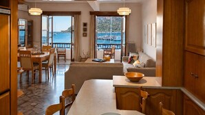 A spacious room with a dining area, a sofa, and a view of the sea. - Matroni's House - Seafront Getaway in Monemvasia (Gefira)